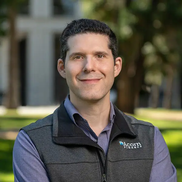 Smiling man's professional headshot in collared shirt and vest.