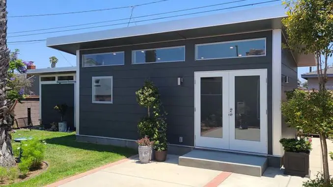 Modern single-story gray house with large windows featured in Finance News.
