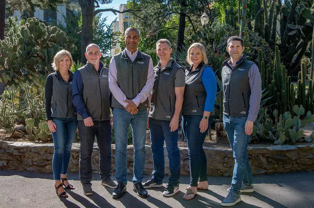 Six people smiling in a cacti garden for Acorn Finance.
