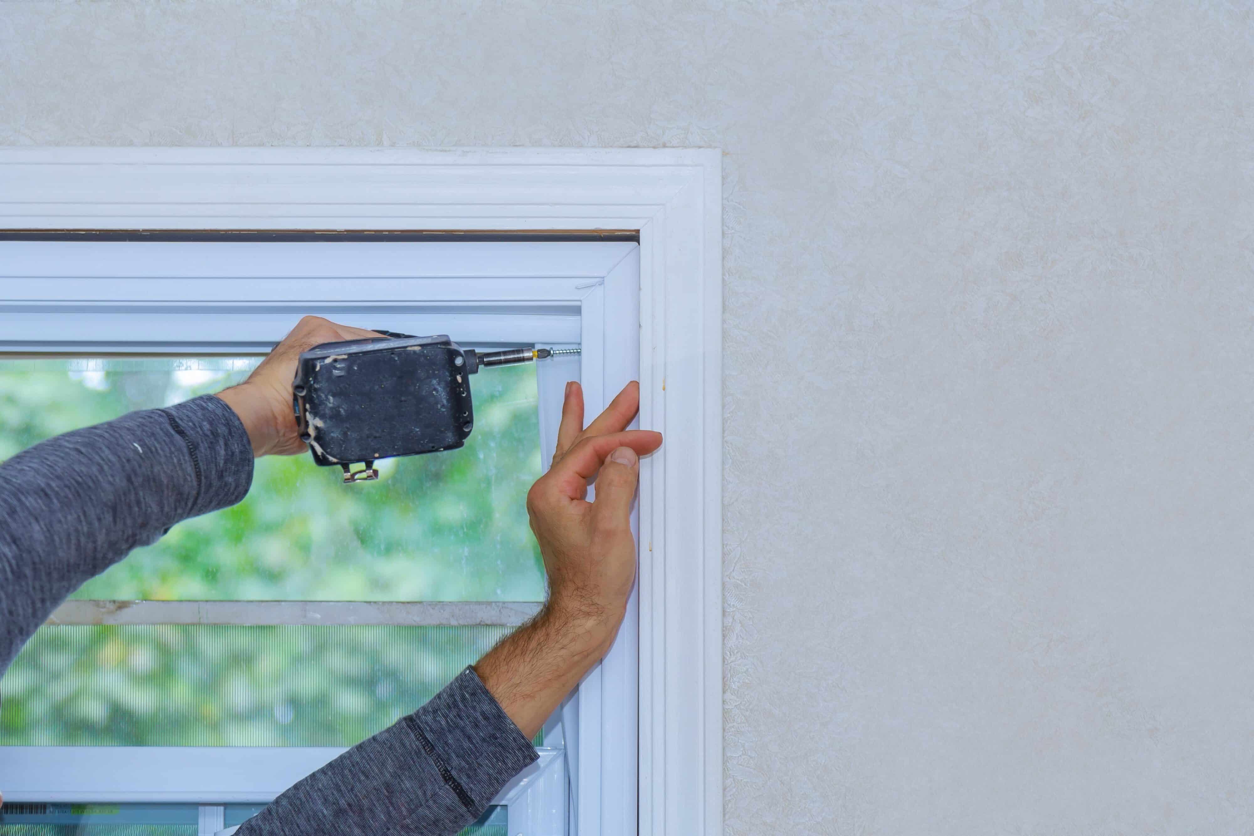 Hand installs window latch with drill during replacement.